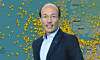 A man in a suit stands in front of a Europe map covered with yellow markers.