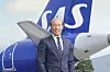 SAS-företrädare i kostym står framför ett flygplan med SAS-logotyp på stjärtfenan.
