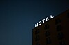Upplyst hotellskylt på en byggnad mot mörk blå kvällshimmel.