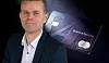 En mand poserer ved siden af et billede af et SAS Business Executive-kort på mørk baggrund.