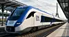 Et hvidt og blåt CDG Express-tog holder ved en overdækket station med Eiffeltårnet i baggrunden.