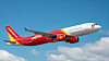 Rødt og hvidt VietJet Air-passagerfly flyver mod blå himmel med skyer.