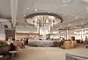 Contemporary hotel lobby with chandelier, marble desk and seating area.