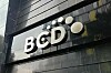 BCD Travel-logotyp i vita bokstäver på en mörk byggnadsfasad.