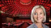 Portrait of Satu Andersson in front of a red-lit auditorium with rows of tables and seats.