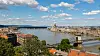 Donaufloden rinner genom en Budapest med broar, byggnader och molnig himmel.