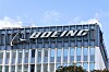 Boeing-logga på toppen av en modern glas- och metallbyggnad mot blå himmel.
