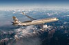 Etihad Airbus A321LR flyger över snötäckta berg och moln.