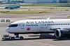 Air Canadan matkustajakone lentoaseman asematasolla, taustalla kiitotie ja rakennuksia.