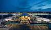 Oslo Lufthavn Gardermoens terminal sedd från luften i kvällsljus, med flygplan och taxibanor.