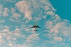 Passagerarflygplan sett underifrån mot en blå himmel med vita moln.