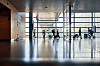 Travellers sit and walk through the bright glass-walled interior of Stockholm Arlanda Airport.