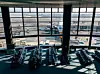 Flygplatsterminal med sittplatser och flygplan synliga genom stora fönster.